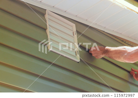 Wall facade of new house is covered with vinyl plastic siding panels installed by construction worker 115972997