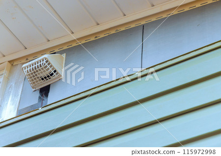 Installing vinyl siding plastic panels on facade wall of new home by an employee 115972998