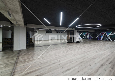 An empty dance hall with a glass wall adorned with decorative graffiti, offering a fusion of contemporary, urban artistic ambiance and impressive aesthetics. 115972999