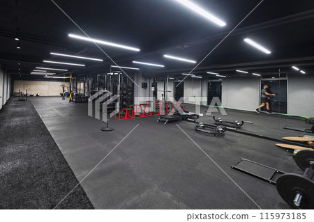 An empty modern gymnasium with a variety of equipment, offering a spacious, functional, and well-equipped training facility for workouts, fitness, and strength training 115973185