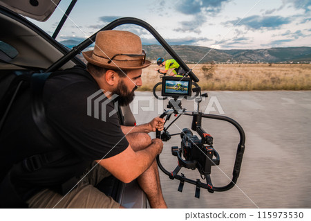 A videographer recording a triathlete riding his bike preparing for an upcoming marathon.Athlete's physical endurance and the dedication required to succeed in the sport. A videographer recording a triathlete riding his bike preparing for an upcoming marathon.Athlete's physical endurance and the dedication required to succeed in the sport. 115973530