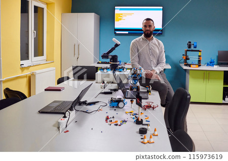 A bearded man in a modern robotics laboratory, immersed in research and surrounded by advanced technology and equipment. 115973619