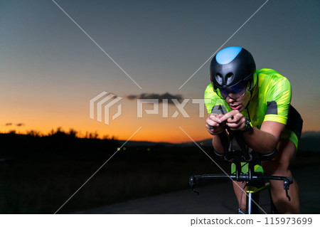 A triathlete rides his bike in the darkness of night, pushing himself to prepare for a marathon. The contrast between the darkness and the light of his bike creates a sense of drama and highlights the A triathlete rides his bike in the darkness of night, pushing himself to prepare for a marathon. The contrast between the darkness and the light of his bike creates a sense of drama and highlights the 115973699