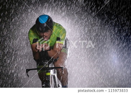 A triathlete braving the rain as he cycles through the night, preparing himself for the upcoming marathon 115973833