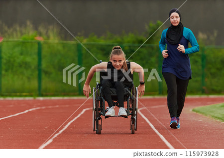 A Muslim woman in a burqa running together with a woman in a wheelchair on the marathon course, preparing for future competitions. 115973928