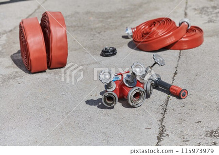 Coiled Fire Hose Ready for Action on the Ground Coiled Fire Hose Ready for Action on the Ground 115973979