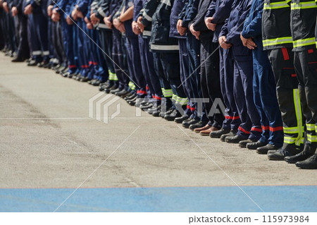 A group of firefighters lined up, saluting the flag, applauding in solidarity, and gearing up for intensive training sessions, showcasing their unwavering commitment to service and teamwork. 115973984