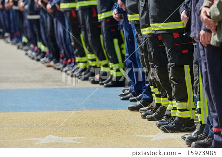 A group of firefighters lined up, saluting the flag, applauding in solidarity, and gearing up for intensive training sessions, showcasing their unwavering commitment to service and teamwork. 115973985