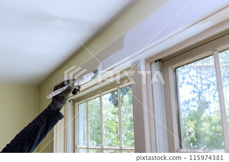 Brush is used to paint window moldings with white paint 115974381
