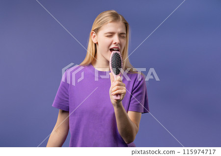 Woman singing, dancing with hair brush instead microphone on Violet background Woman singing, dancing with hair brush instead microphone on Violet background 115974717