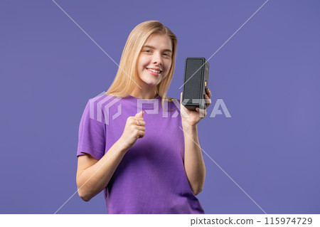 Blonde woman listening music by wireless portable speaker - sound system, violet Blonde woman listening music by wireless portable speaker - sound system, violet 115974729