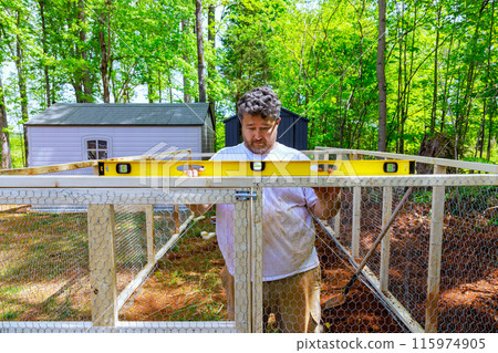Farmer constructs an outdoor chicken coop for his chickens using level Farmer constructs an outdoor chicken coop for his chickens using level 115974905