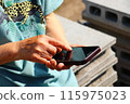 My mother's hands operating a smartphone 115975023