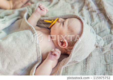 Baby after shower wrapped in a towel. This adorable moment captures the freshness and comfort of a clean baby, highlighting the tender care and love in the daily routine 115975752