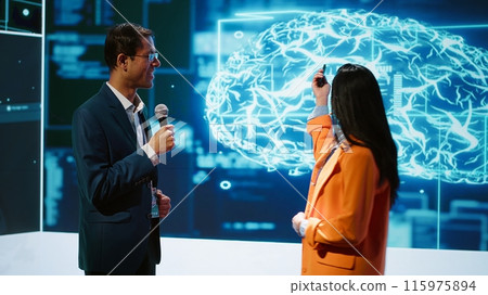 Presenter and guest chatting during AI summit discussion panel bringing together tech companies, exploring latest developments in artificial intelligence industry and emerging technologies, camera A 115975894
