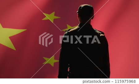 Soldier doing salute hand gesture towards Chinese flag, feeling pride in serving country. China army personnel does military greeting gesturing while listening national anthem, camera A 115975968