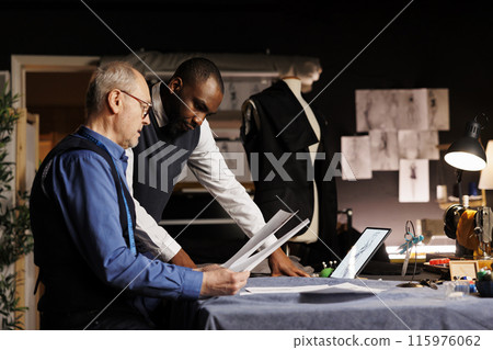 Tailors checking fashion sketch designs, trying different attire combinations on mannequin in haute couture atelier. Master craftsman and apprentice working on bespoke suit alterations Tailors checking fashion sketch designs, trying different attire combinations on mannequin in haute couture atelier. Master craftsman and apprentice working on bespoke suit alterations 115976062