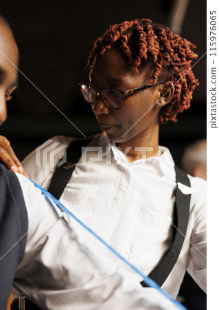Close up of professional seamstress measuring customer arm length to figure needed sartorial piece size. Experienced meticulous tailor involved in premium quality craftmanship comission 115976065