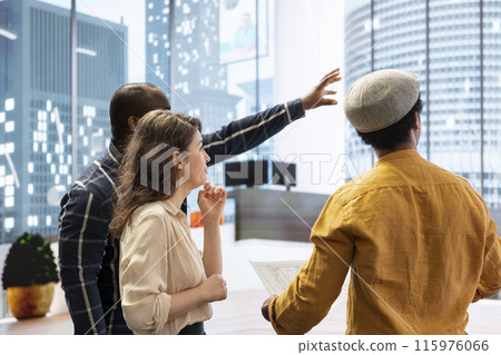 Realtor and clients sharing workspace design vision on an office tour, evaluating modern property layout and blueprints before moving to a high class urban setting. Leasing contract negotiation. 115976066