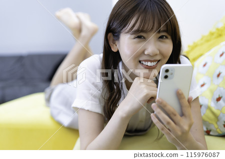 一個女人躺在沙發上使用智慧型手機 115976087