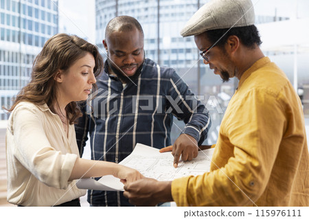 Business partners touring an office space with realtor and layout plans, focusing on architectural blueprints and planning a property investment. Realtor evaluating modern high class building. 115976111