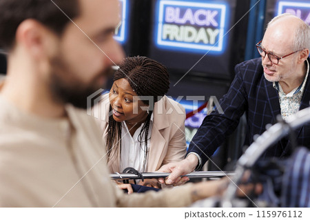 Rude unpleasant shoppers arguing and fighting while hunting for Black Friday deals in clothing store, grabbing discounted fashion items and yelling at each other. People fight over clothes in mall 115976112