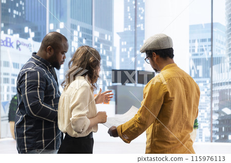 Business team and a real estate agent strategizing the relocation of a corporate office, reviewing detailed blueprints and planning design and layout of the new workspace. New investment strategy. 115976113