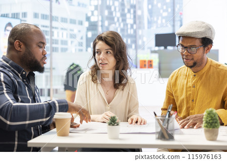 Professional brokers and client discussing rental investment strategy during an office tour, evaluating architectural blueprints for a high class corporate office space. Workspace relocation. 115976163