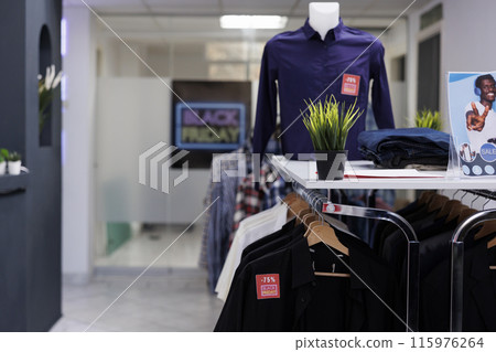 Empty clothing store decorated for discount season ready for opening on Black Friday, nobody. Clothes with red sale price tags hanging on racks, retail business and seasonal sales 115976264