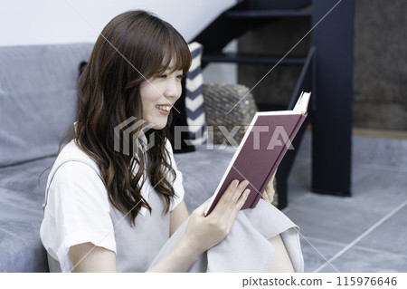 A woman reading a book in the living room A woman reading a book in the living room 115976646