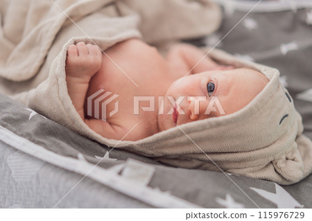 Baby after shower wrapped in a towel. This adorable moment captures the freshness and comfort of a clean baby, highlighting the tender care and love in the daily routine 115976729