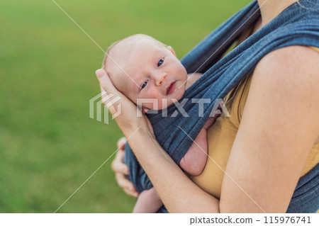 Mom walks with her newborn baby in a sling. This moment highlights the close bond between mother and child, promoting comfort, security, and the benefits of babywearing in everyday life 115976741