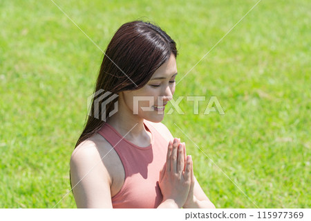 Woman doing yoga in green park (outdoor portrait, relaxing) 115977369
