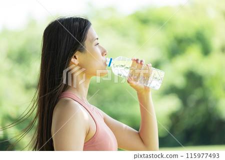 Woman hydrating in green park (outdoor portrait, resting, relaxing) 115977493
