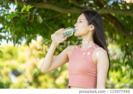Woman hydrating in green park (outdoor portrait, resting, relaxing) 115977498