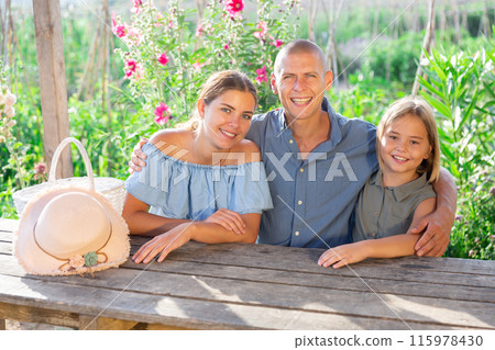 Family sitting at table in garden 115978430