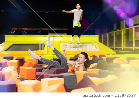 Woman laughing while landing in foam pit at trampoline park Woman laughing while landing in foam pit at trampoline park 115978557