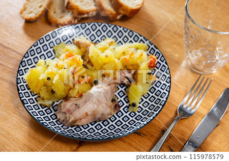 Lunch is served on plate - pieces of young rabbit cooked with segments of potato. Close-up Lunch is served on plate - pieces of young rabbit cooked with segments of potato. Close-up 115978579