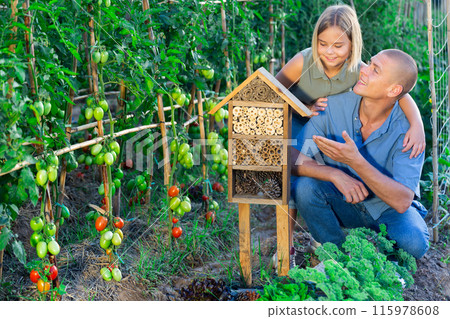 Father and little daughter are happy with the made hotel for insects Father and little daughter are happy with the made hotel for insects 115978608