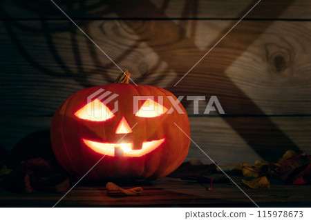 Halloween Pumpkin Jack-O-Lantern in a wooden barn with shadows on the wall 115978673