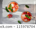 Summer refreshing homemade cocktail with strawberries and mint on the table in a bright kitchen 115978704