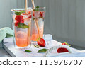 Summer refreshing homemade cocktail with strawberries and mint on the table in a bright summer kitchen in the garden, copyspace 115978707