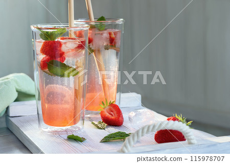 Summer refreshing homemade cocktail with strawberries and mint on the table in a bright summer kitchen in the garden, copyspace Summer refreshing homemade cocktail with strawberries and mint on the table in a bright summer kitchen in the garden, copyspace 115978707