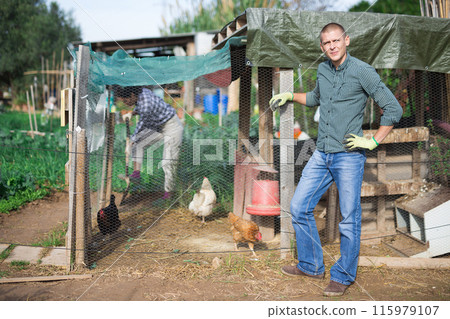 Confident male smallholding owner standing near hen house Confident male smallholding owner standing near hen house 115979107