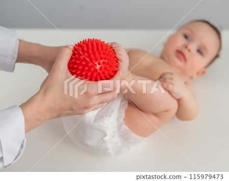 A doctor massages a baby's foot using a spiked ball. A doctor massages a baby's foot using a spiked ball. 115979473