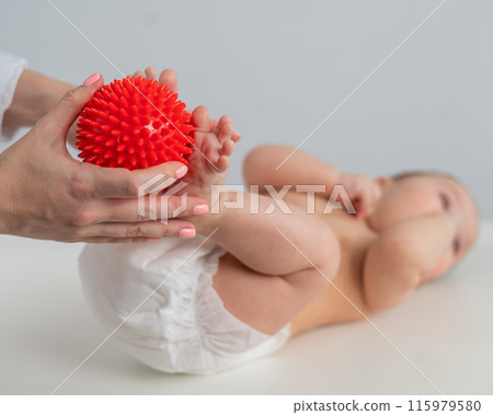 A doctor massages a baby's foot using a spiked ball. 115979580