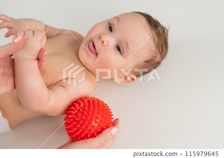 A doctor gives a baby a shoulder massage using a ball. A doctor gives a baby a shoulder massage using a ball. 115979645