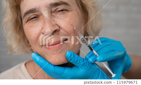 Doctor makes beauty injections in the face of an old caucasian woman. Doctor makes beauty injections in the face of an old caucasian woman. 115979671
