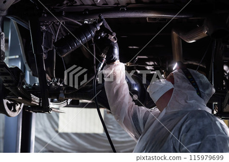 The master sprays an anti-corrosion compound on the bottom of the car.  115979699