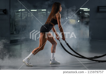 Caucasian woman doing exercise with ropes. Circuit training in the gym. 115979757